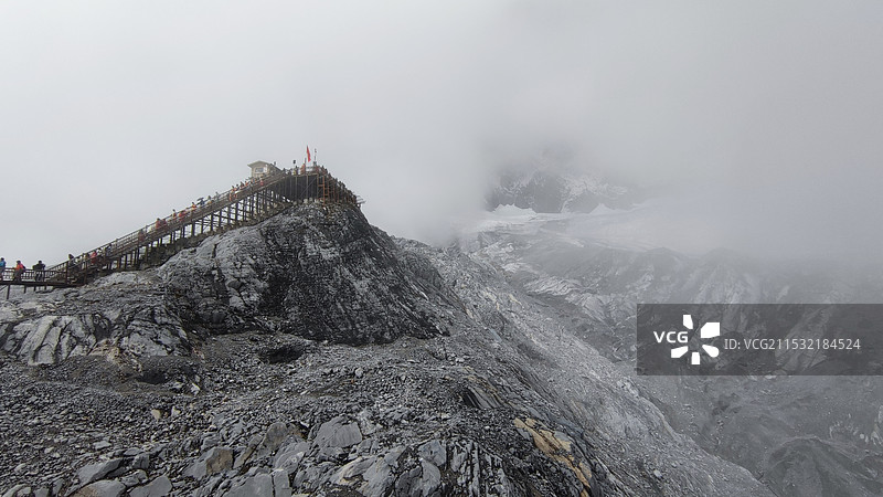 丽江玉龙雪山白雪皑皑的山顶上沿着登上栈道正在努力登顶的人们在大雾中的特写图片素材