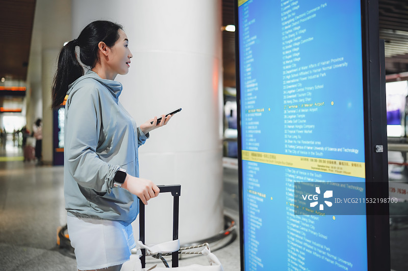 一名女子在机场候机楼查看航班时刻表图片素材