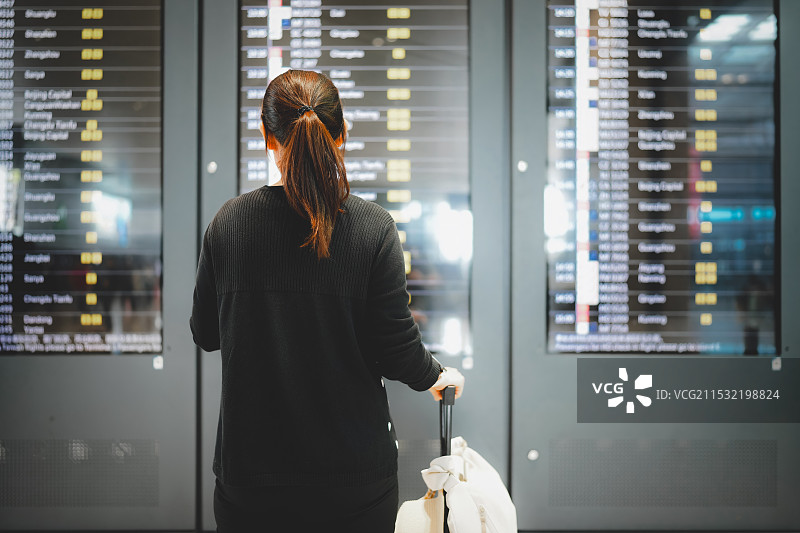 一名女子在机场候机楼查看航班时刻表图片素材