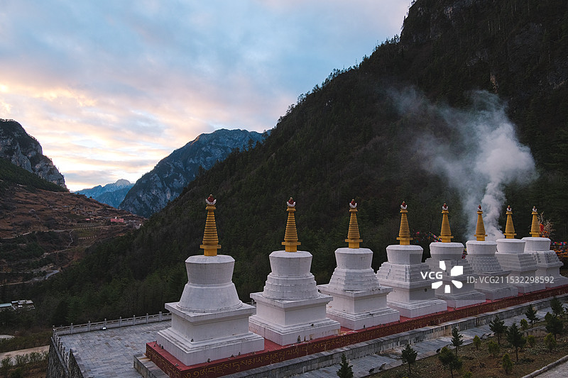 云南迪庆香格里拉巴拉格宗大峡谷群山中的一排佛塔与祭祀时燃烧产生的烟雾图片素材