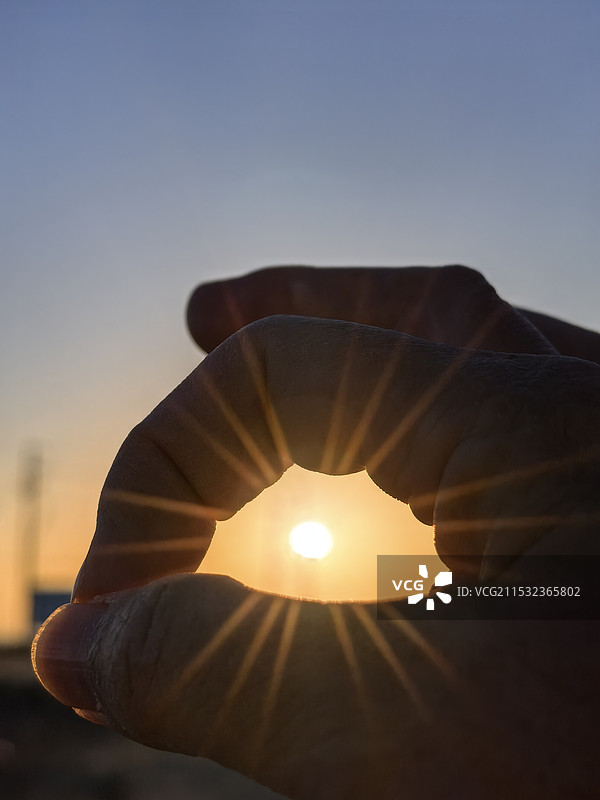 日出时手对着天空的特写镜头图片素材