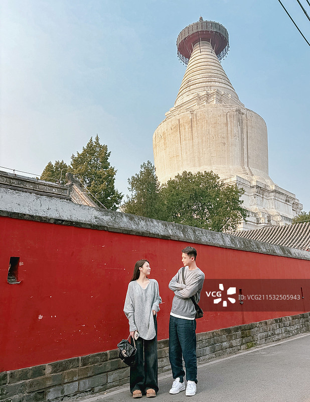 北京白塔寺墙外驻足相视微笑的男女图片素材