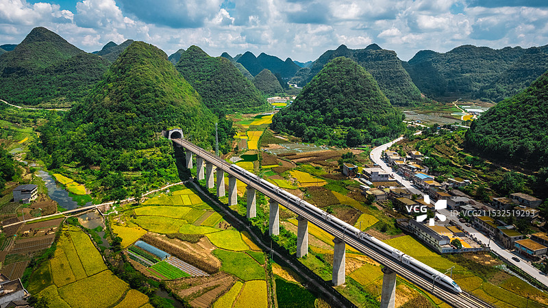 蓝天白云贵州万峰林间穿行的高铁火车和田野图片素材