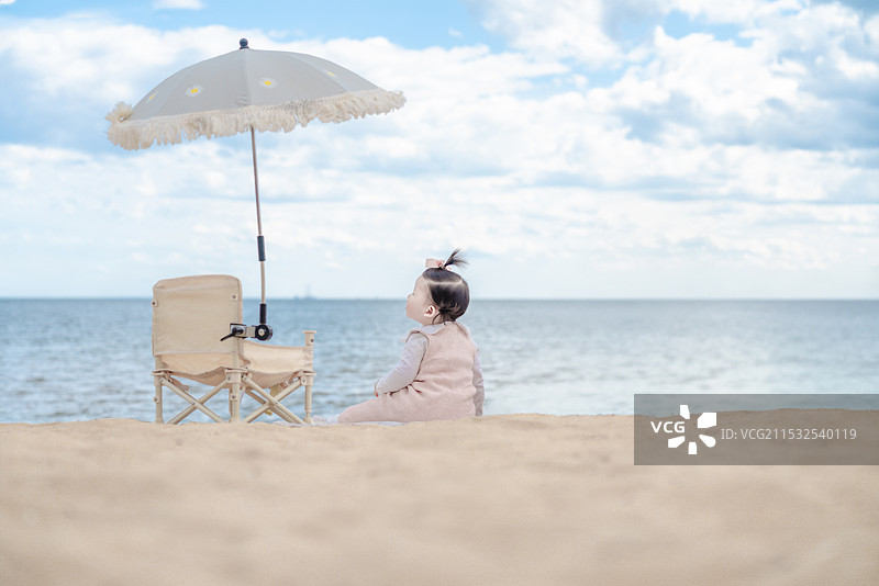 大海沙滩上遮阳伞处观海景的可爱女婴娃图片素材