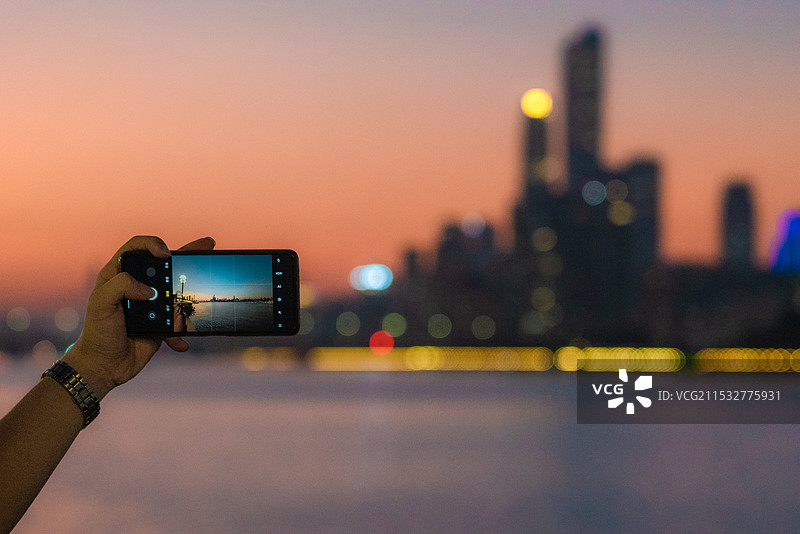 日落时用手机拍摄城市景观广州塔珠江新城广州江边日落图片素材