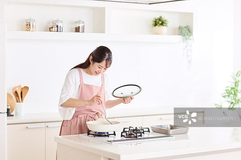 穿围裙的日本女性在炉子上烹饪图片素材