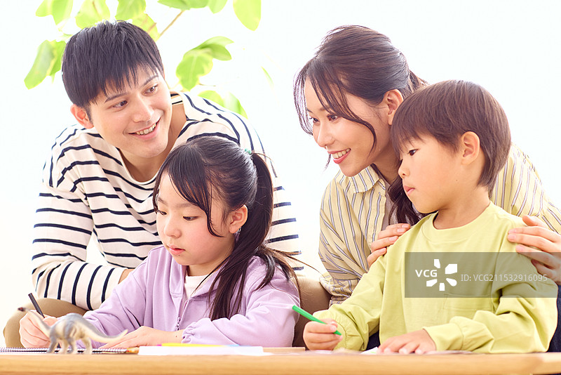 日本家庭坐在桌子旁，孩子们在画画。图片素材