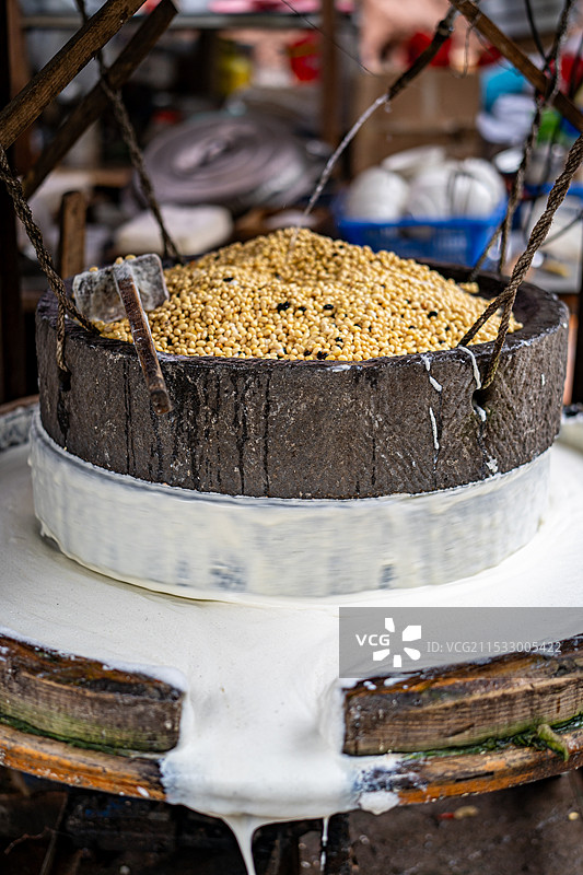 磨盘中研磨中的豆子和溢出的豆浆图片素材