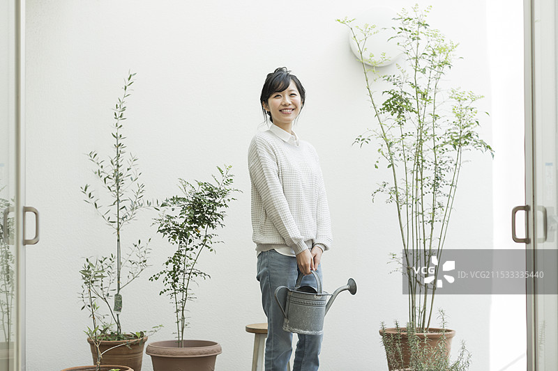 女人在阳台上拿着浇水壶图片素材