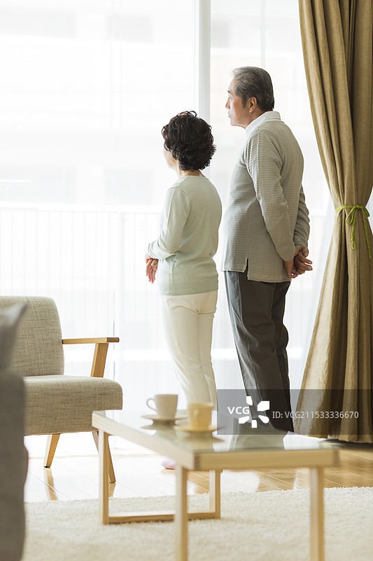 老年夫妇站在窗边眺望外面图片素材