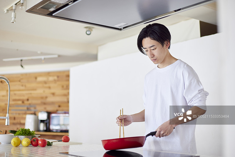年轻的日本男子在厨房里做饭图片素材