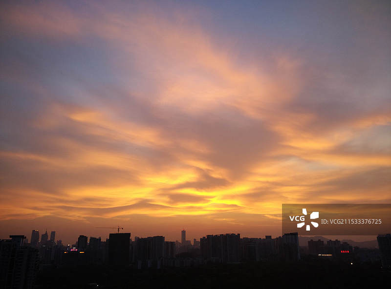 日落时建筑物在多云梦幻晚霞天空下的轮廓图片素材