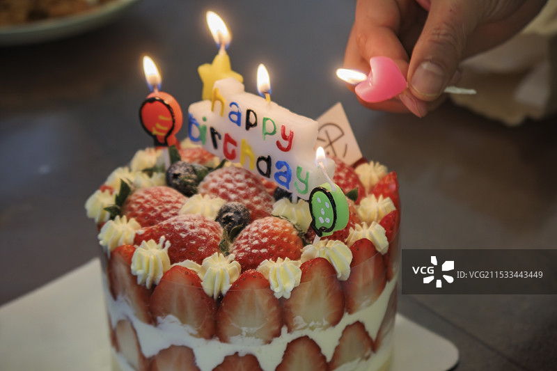 给生日蛋糕点蜡烛，草莓水果蛋糕点燃蜡烛图片素材
