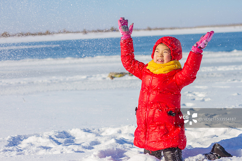 晴朗的冬日里玩雪的红衣小女孩图片素材