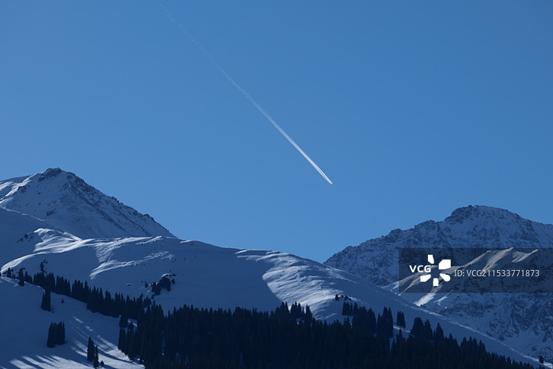 飞机的印记留在那拉提草原的雪山上空宛若白日流星图片素材