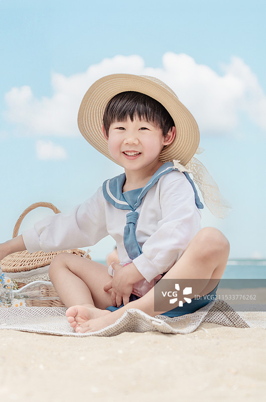 坐在海边沙滩上乐呵呵的可爱小男孩图片素材