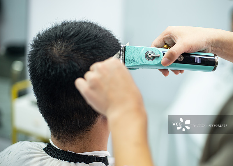 中国家庭生活拍摄主题，理发剃头手艺，理发师正在用剪刀和推子给顾客剪头发，户外白昼无人图像摄影图片素材