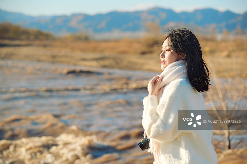 拿着相机的美女摄影师在深秋的户外拍摄图片素材