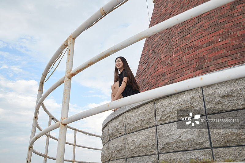 盛夏在景区湖边灯塔上拍照游玩的美女图片素材