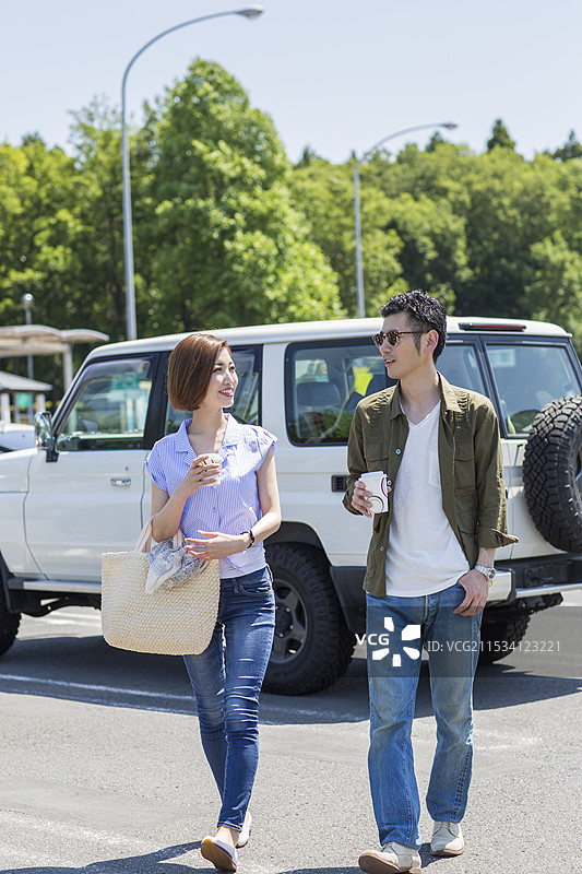 二三十岁的情侣在户外停车场喝咖啡图片素材