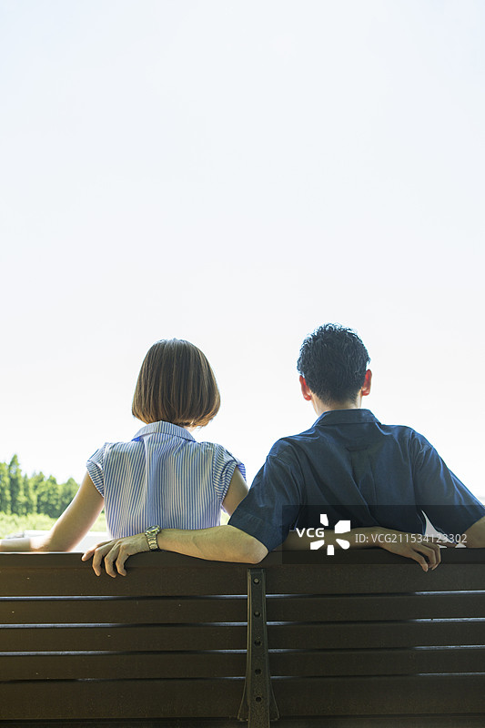 二三十岁的情侣坐在长椅上，背影。图片素材