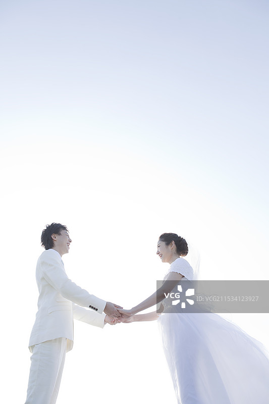 新娘和新郎面对面，手牵着手图片素材