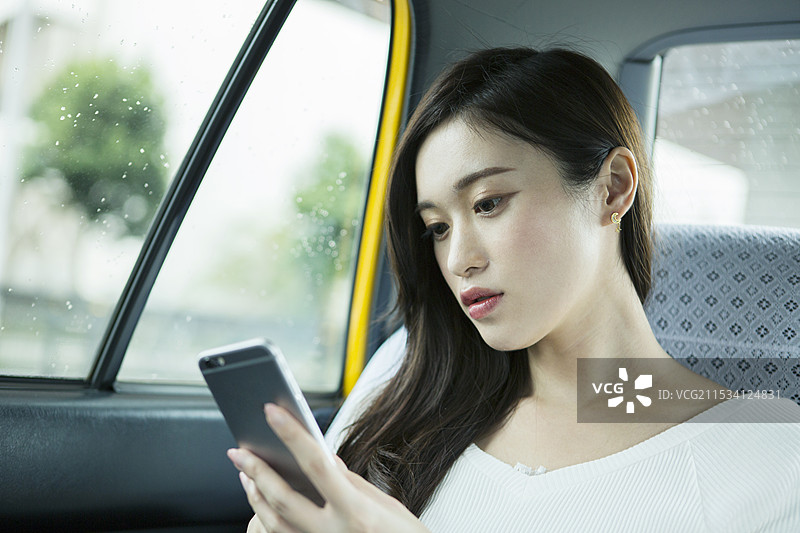 20多岁的女性在出租车内使用智能手机图片素材