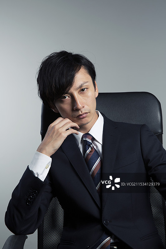 坐在椅子上，面带微笑的男子正看着镜头，颧骨突出。图片素材