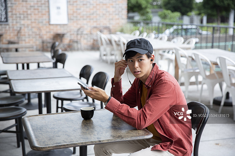 20多岁的男子在咖啡馆里看手机图片素材