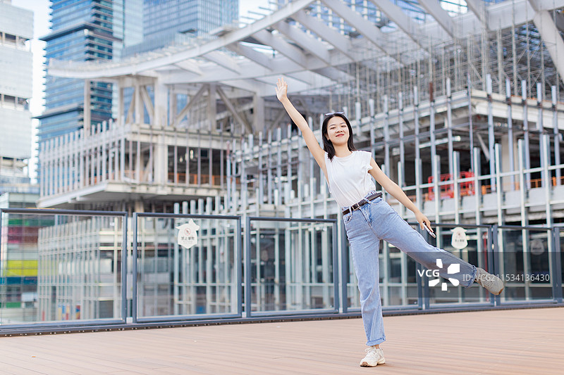 女生拿着手机在城市建筑广场图片素材