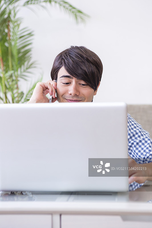 一名男子在使用电脑时打电话图片素材