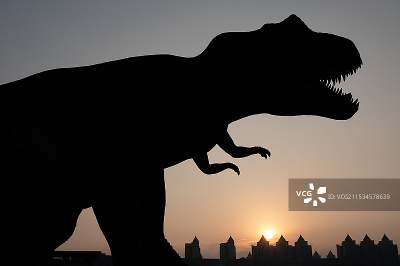 夕阳下的恐龙与脚下的城市图片素材
