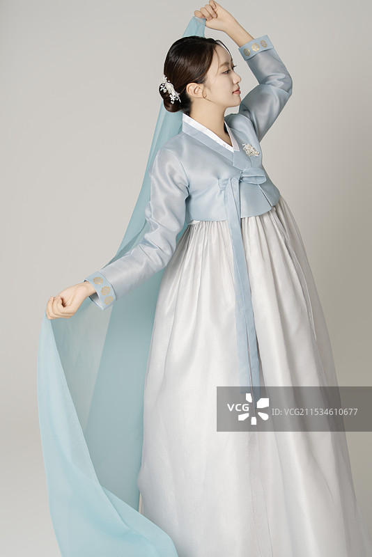 一位美丽的女性穿着华丽优雅的汉服，手中舞动着一条蓝色布料。图片素材