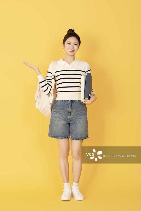 一名穿着休闲服的大学生与一本书摆姿势图片素材