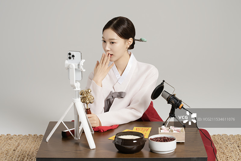 一位年轻的萨满手持萨满铃，正在进行直播。图片素材