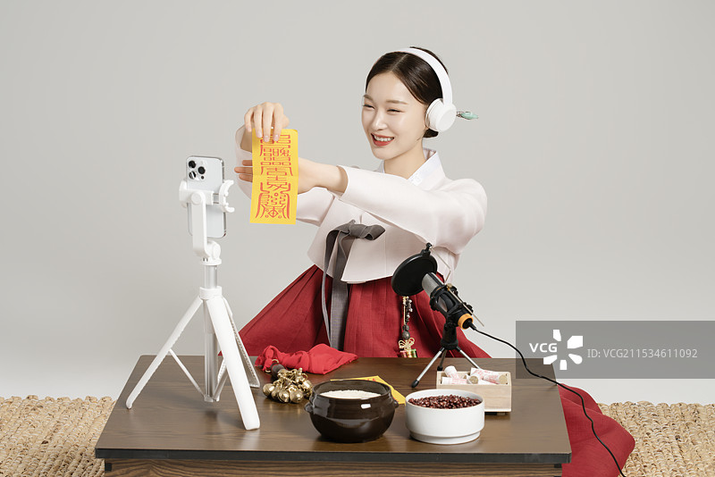一位年轻的萨满戴着耳机，边展示护身符边进行直播。图片素材