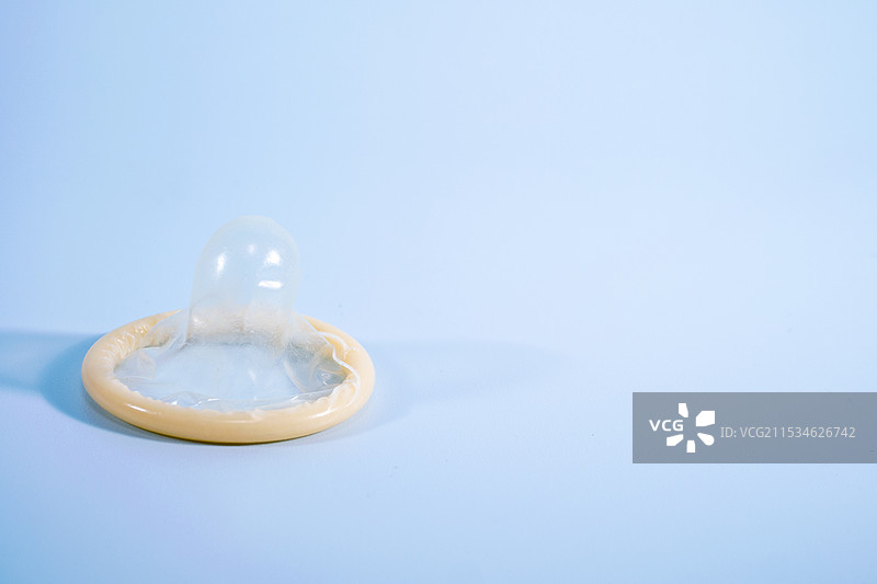 一个安全套在蓝色背景上。使用避孕套可以显着降低患淋病、衣原体、毛癣菌病、B型肝炎和艾滋病毒风险图片素材