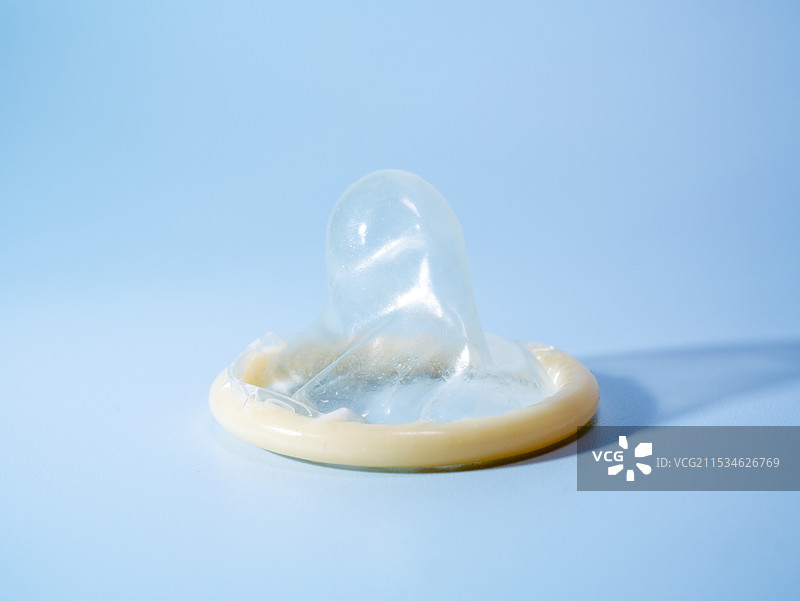 一个安全套在蓝色背景上。使用避孕套可以显着降低患淋病、衣原体、毛癣菌病、B型肝炎和艾滋病毒风险图片素材