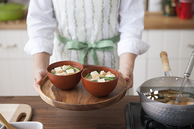 女人手持托盘上的味噌汤碗图片素材