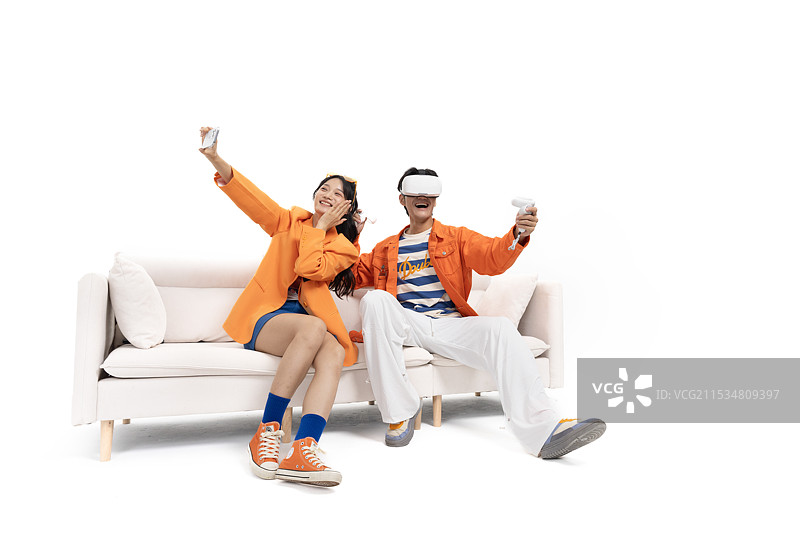 玩VR游戏的亚洲男孩与用手机拍摄的亚洲女孩图片素材