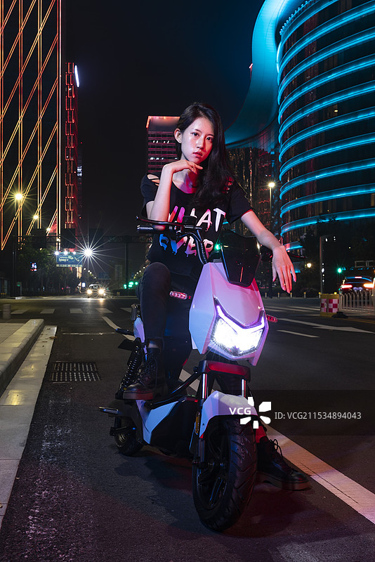 夜晚骑着电动车的年轻女孩图片素材