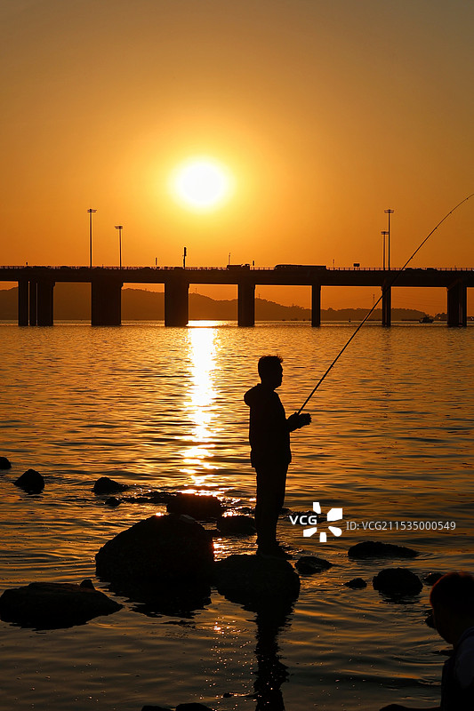 夕阳下海上垂钓的剪影图片素材