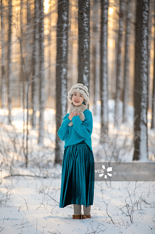 穿着暖和衣服的东方美女站在雪地上图片素材