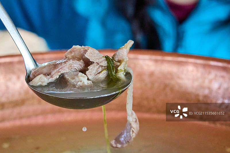 云南特色铜瓢火锅中汤勺捞起的肉图片素材