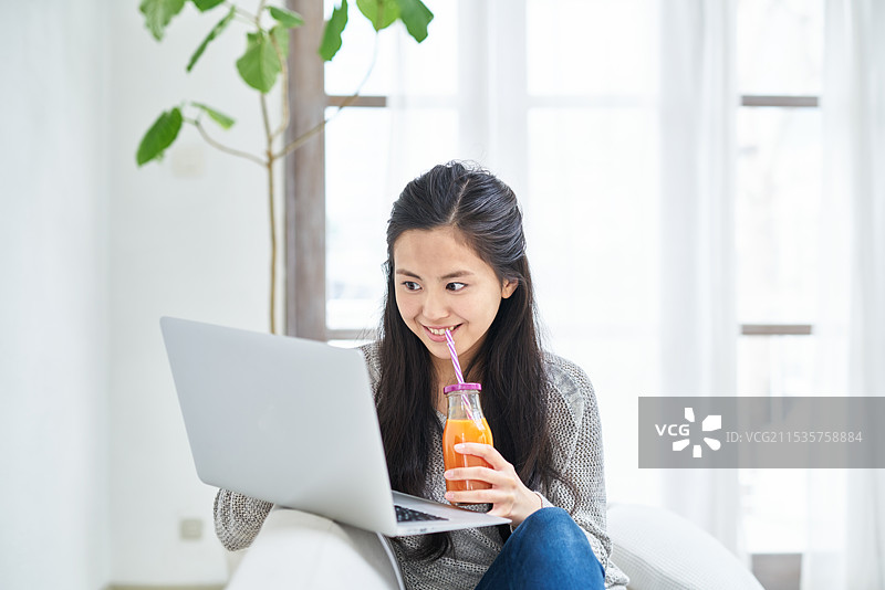 女人坐在沙发上使用电脑图片素材