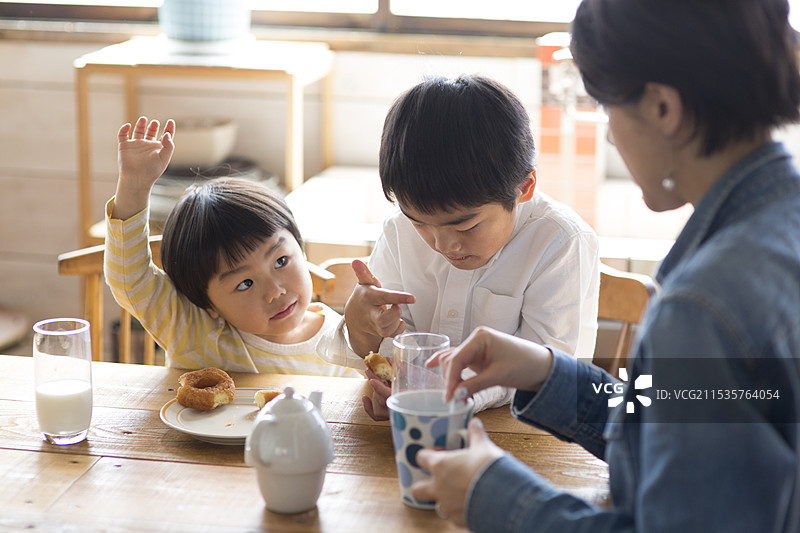 兄弟姐妹和母亲在厨房桌子上吃零食图片素材