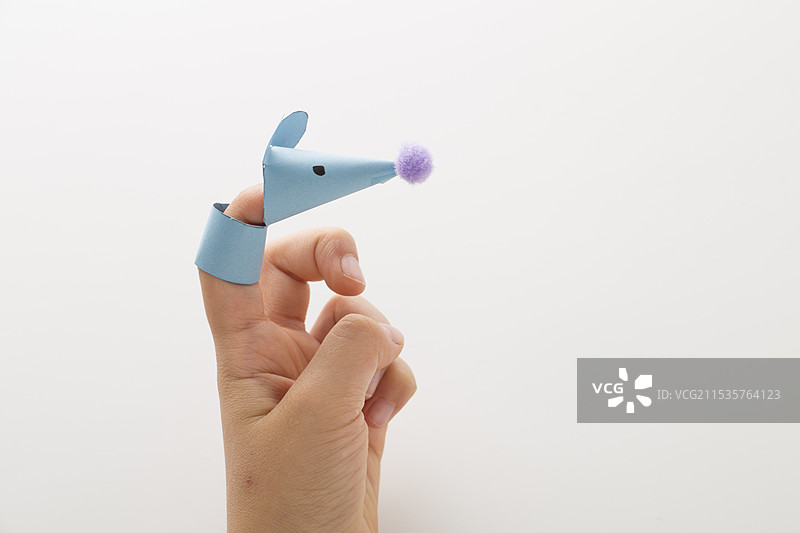 一个孩子的手上戴着一个手工制作的手指木偶老鼠。图片素材