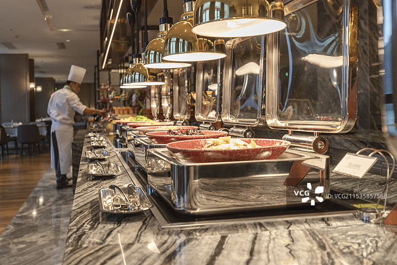 五星级酒店高档自助餐厅的餐台，背景厨师正在摆放食物，豪华自助餐图片素材
