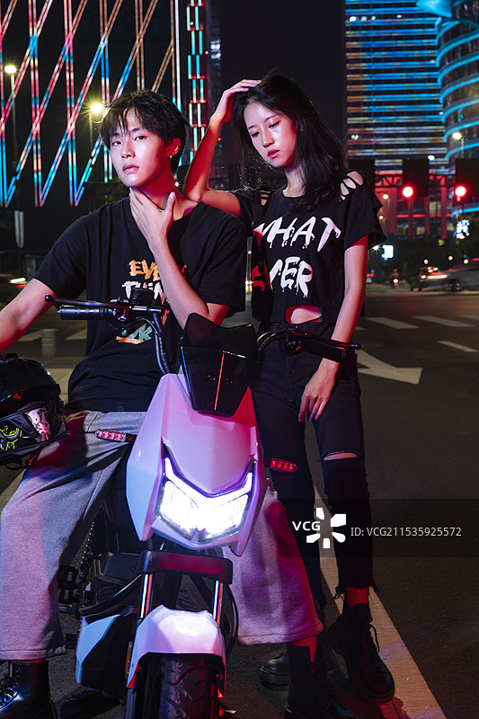 夜晚骑着电动车的年轻情侣图片素材