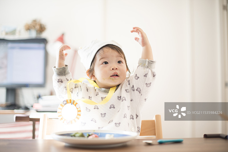 生日的小孩在用餐时仰望着，做出万岁手势图片素材